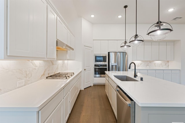 kitchen with a center island with sink, visible vents, stainless steel appliances, wall chimney range hood, and a sink