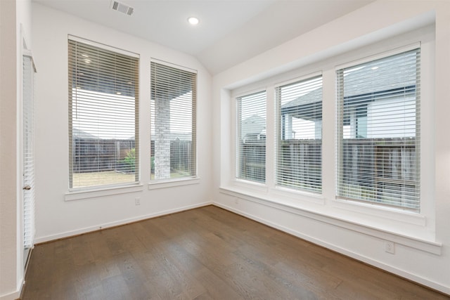 empty room with dark wood-type flooring, lofted ceiling, visible vents, and baseboards