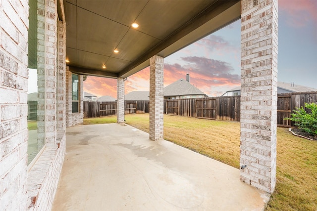 patio terrace at dusk with a fenced backyard and a yard