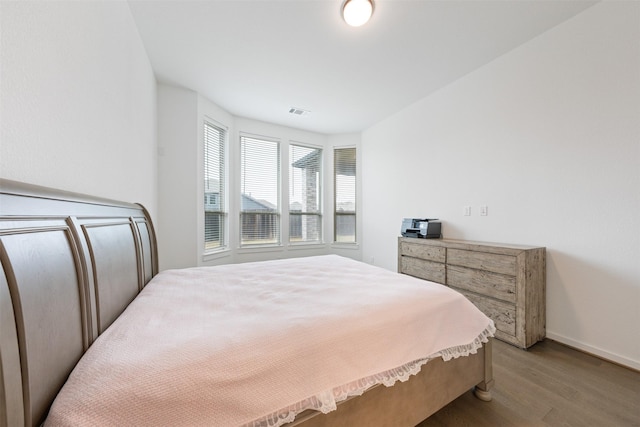 bedroom with light wood finished floors, visible vents, and baseboards