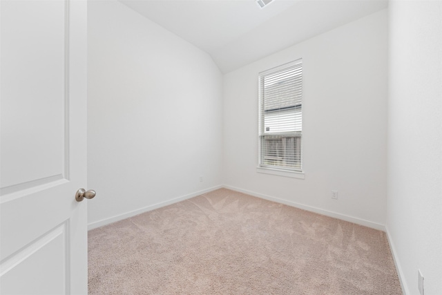 spare room with light carpet, vaulted ceiling, and baseboards