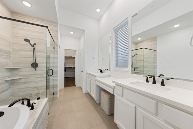 bathroom featuring tiled bath, tile patterned floors, a walk in closet, vanity, and a shower stall