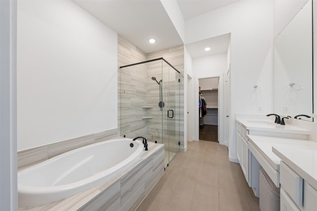 full bathroom featuring a garden tub, vanity, tile patterned floors, a stall shower, and a walk in closet