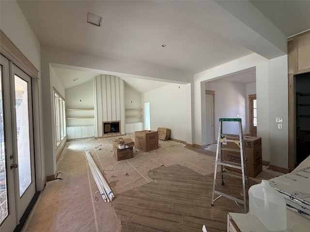 unfurnished living room featuring french doors, a large fireplace, lofted ceiling, and light hardwood / wood-style floors