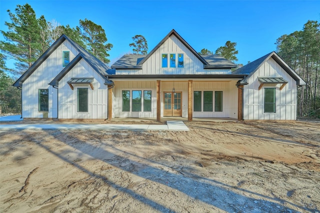 modern inspired farmhouse featuring a standing seam roof, board and batten siding, roof with shingles, and metal roof