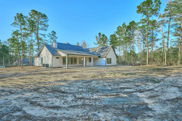 view of front of home featuring central air condition unit, a chimney, and stucco siding