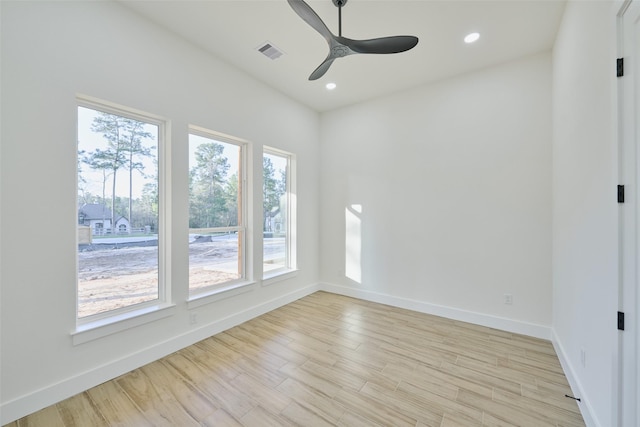 spare room featuring light wood finished floors, visible vents, a ceiling fan, and baseboards