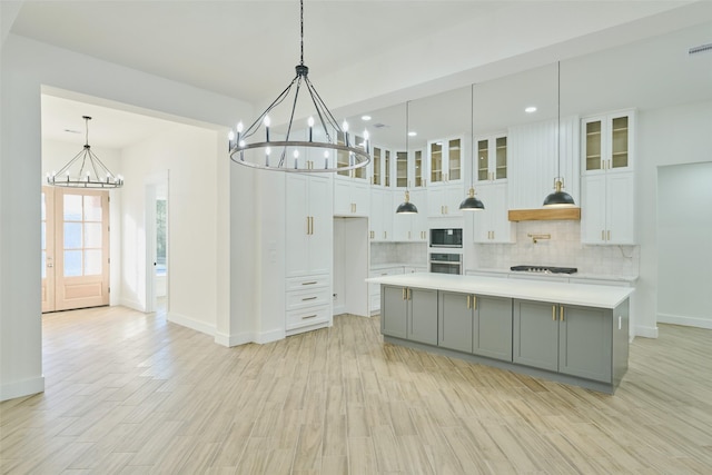 kitchen featuring oven, gray cabinets, backsplash, an inviting chandelier, and built in microwave