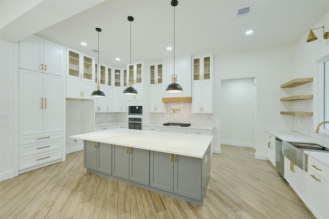 kitchen with gray cabinetry, a sink, open shelves, light countertops, and cooktop