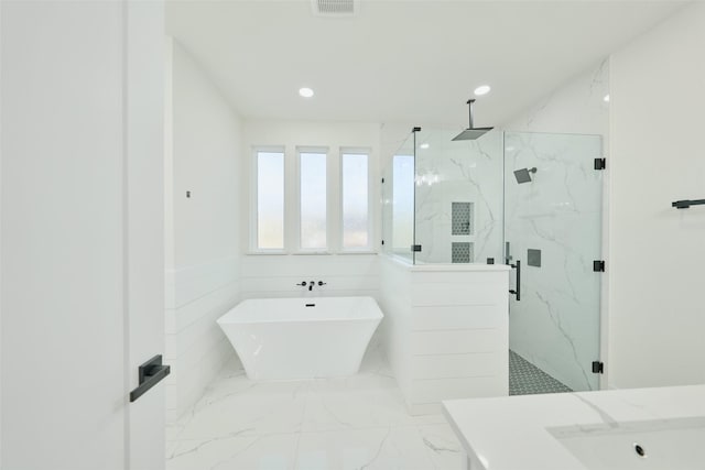 full bath featuring a wainscoted wall, a freestanding tub, marble finish floor, recessed lighting, and a marble finish shower