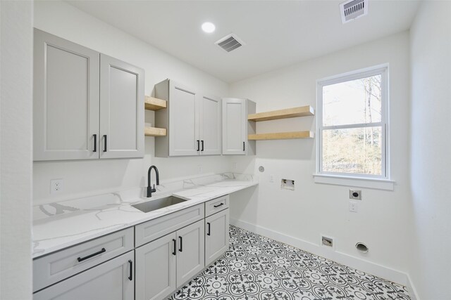 laundry area featuring a sink, visible vents, cabinet space, and hookup for an electric dryer