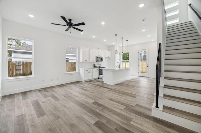 unfurnished living room featuring sink, light hardwood / wood-style flooring, and ceiling fan