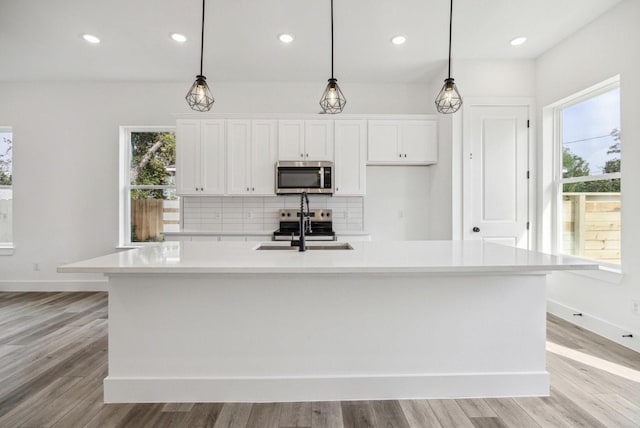 kitchen with white cabinetry, a large island, sink, and decorative light fixtures