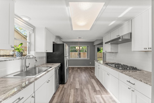 kitchen with sink, white cabinetry, light hardwood / wood-style flooring, stainless steel appliances, and decorative backsplash