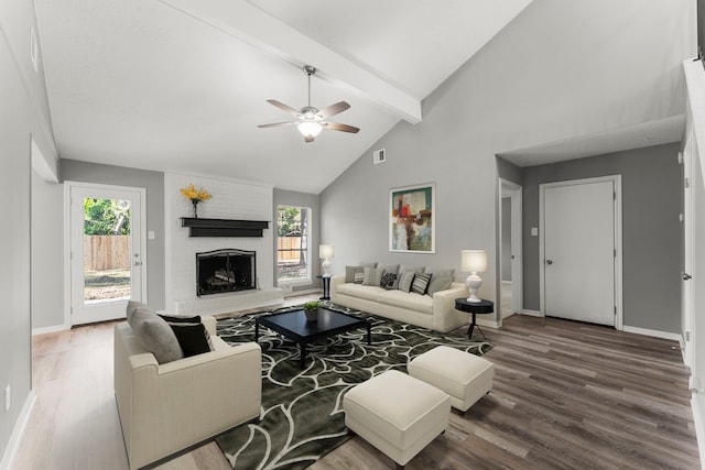 living room featuring high vaulted ceiling, hardwood / wood-style flooring, beamed ceiling, ceiling fan, and a fireplace