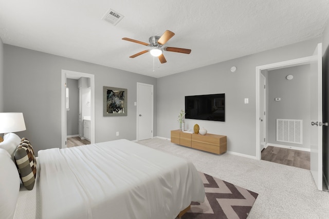 carpeted bedroom with ensuite bath, a textured ceiling, and ceiling fan