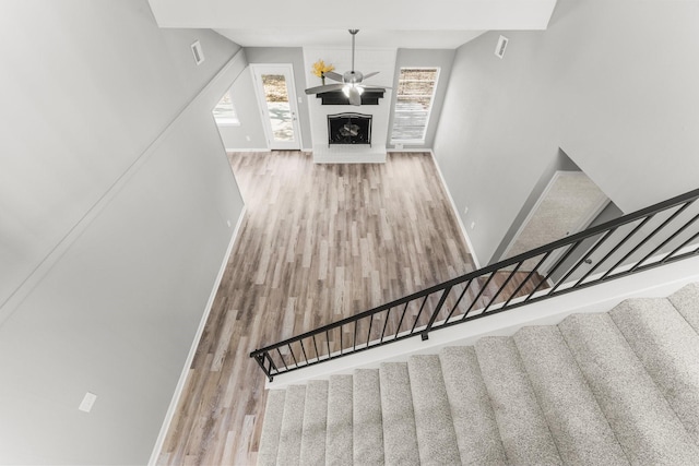 stairway featuring hardwood / wood-style floors, a fireplace, and ceiling fan