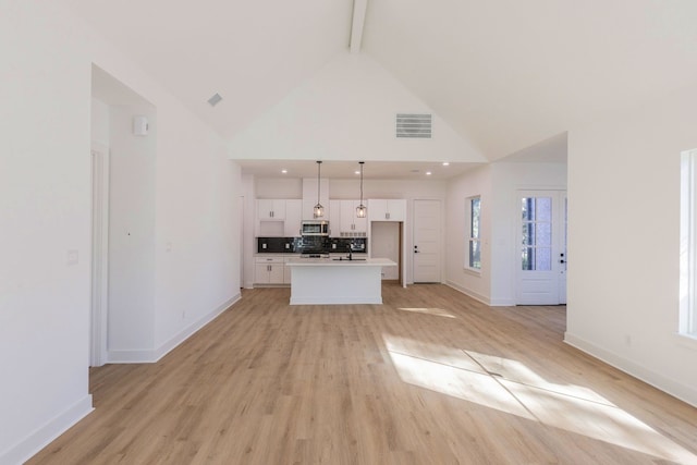 unfurnished living room featuring sink, beam ceiling, high vaulted ceiling, and light hardwood / wood-style flooring