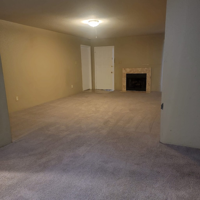 unfurnished living room featuring a fireplace, a textured ceiling, and carpet flooring