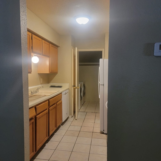 kitchen featuring light tile patterned flooring, white appliances, sink, and washing machine and dryer