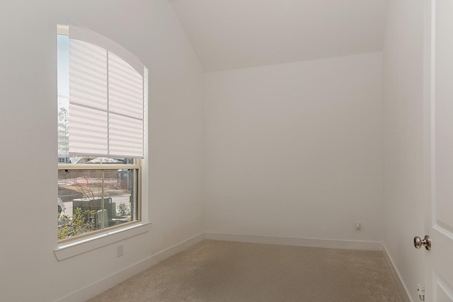 carpeted spare room with lofted ceiling