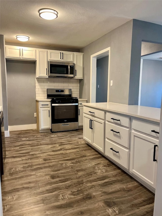 kitchen with backsplash, stainless steel appliances, and white cabinets