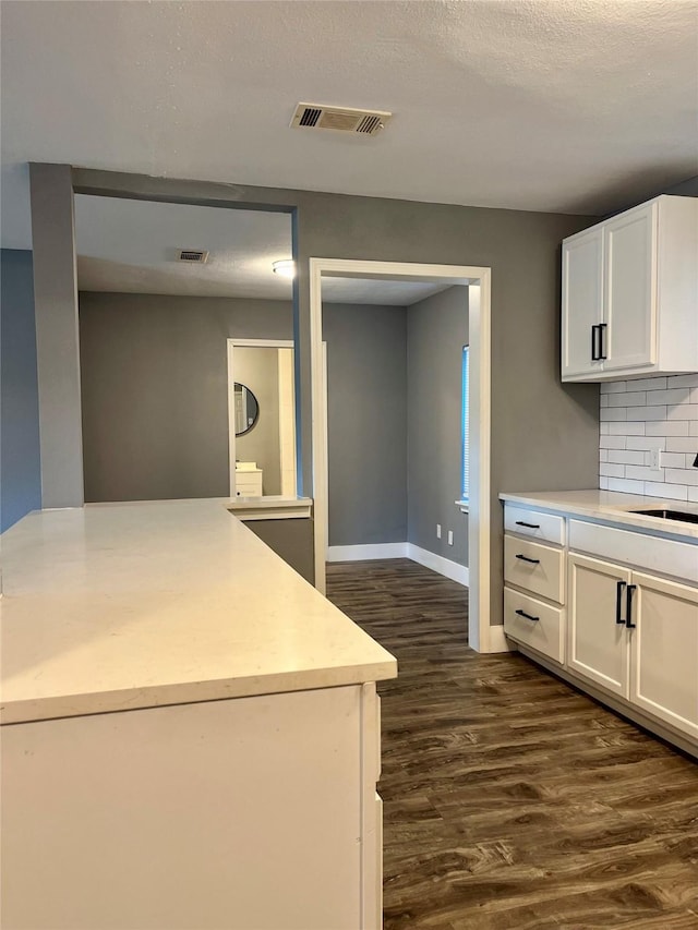 kitchen with dark wood-type flooring, sink, tasteful backsplash, a textured ceiling, and white cabinets