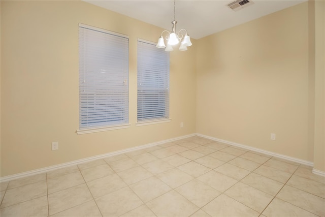 spare room with light tile patterned floors and an inviting chandelier