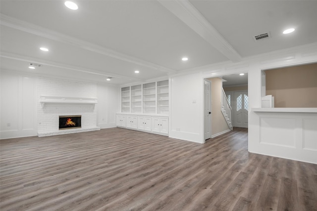 unfurnished living room with crown molding, beam ceiling, wood-type flooring, and built in shelves