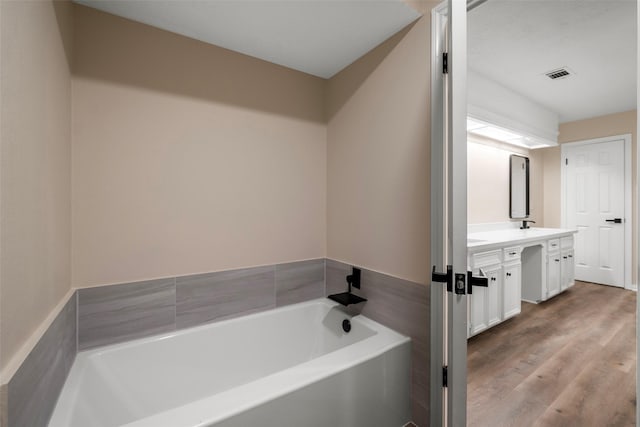 bathroom with vanity, wood-type flooring, and a tub