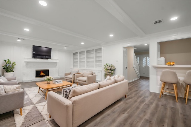 living room featuring crown molding, hardwood / wood-style floors, a fireplace, and beam ceiling