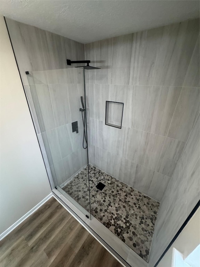 bathroom with hardwood / wood-style flooring, a tile shower, and a textured ceiling