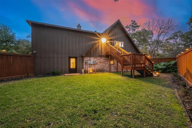 back house at dusk with a yard and a deck