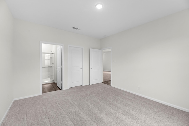 unfurnished bedroom featuring ensuite bath and dark colored carpet