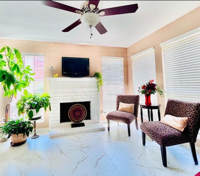 living area featuring a brick fireplace and ceiling fan