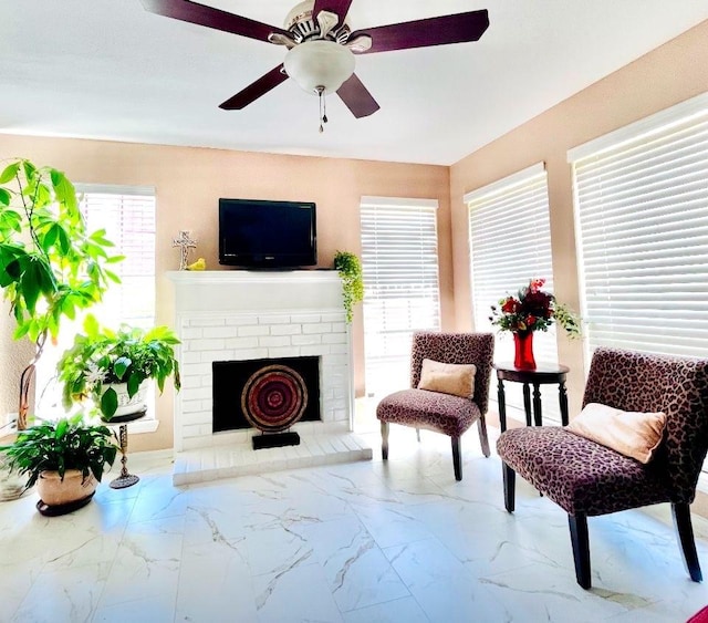 living area with a brick fireplace and ceiling fan