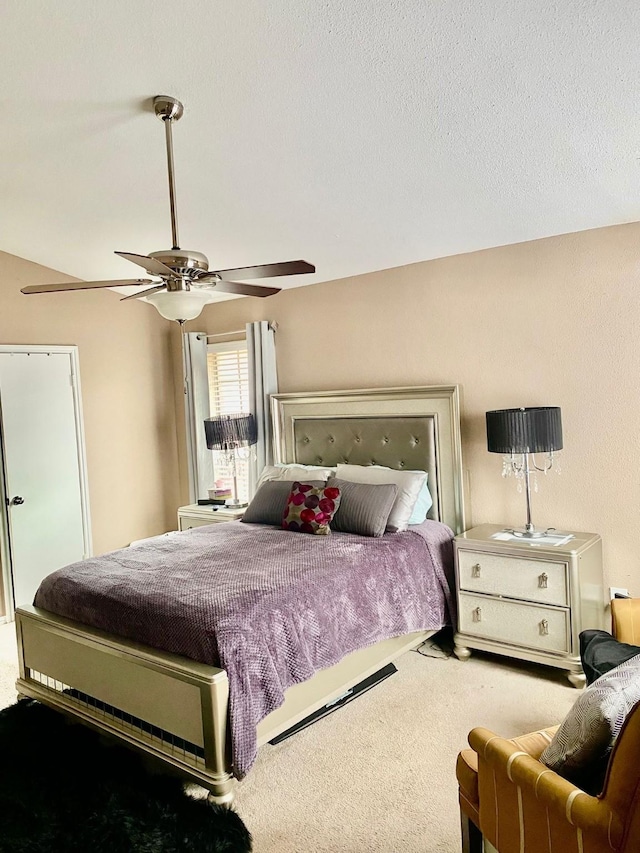 carpeted bedroom with ceiling fan and a textured ceiling