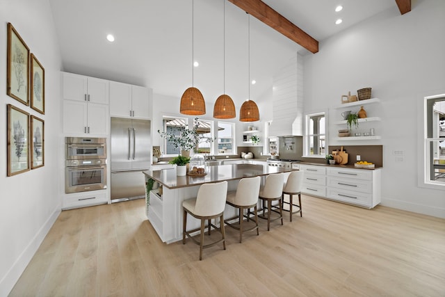 kitchen featuring a center island, hanging light fixtures, appliances with stainless steel finishes, a kitchen breakfast bar, and beam ceiling