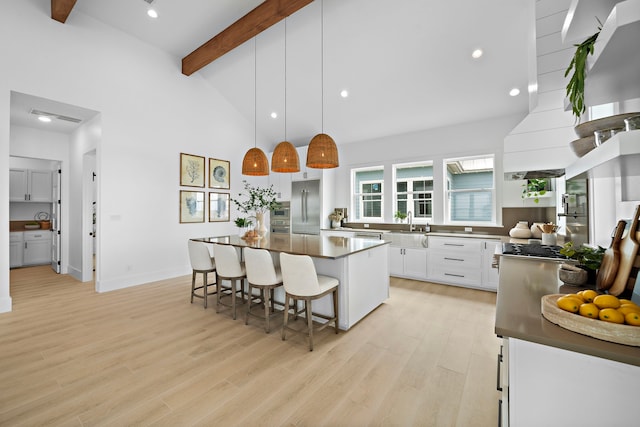 kitchen featuring hanging light fixtures, a kitchen island, beamed ceiling, stainless steel appliances, and white cabinets