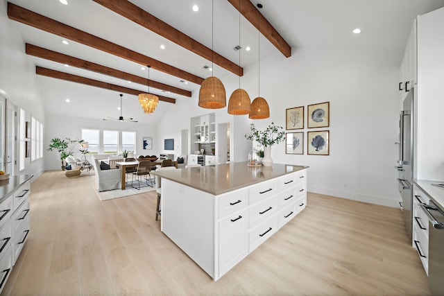 kitchen featuring a spacious island, white cabinetry, decorative light fixtures, beam ceiling, and light hardwood / wood-style floors