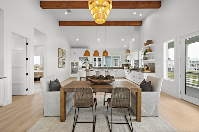 dining room featuring a healthy amount of sunlight, high vaulted ceiling, and light hardwood / wood-style flooring