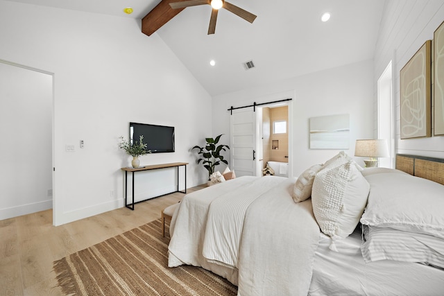 bedroom featuring vaulted ceiling with beams, ensuite bath, light hardwood / wood-style flooring, ceiling fan, and a barn door