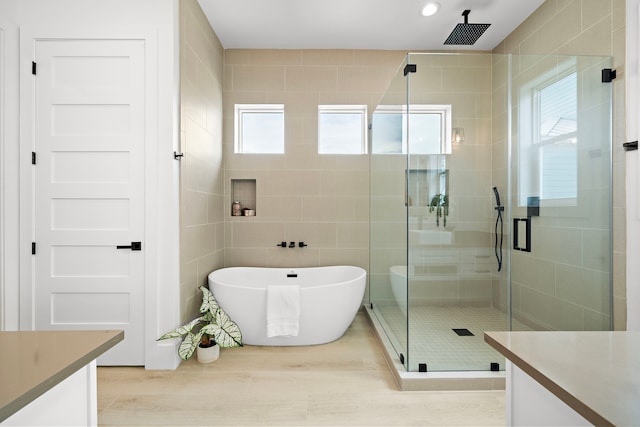 bathroom featuring vanity, hardwood / wood-style floors, tile walls, and plus walk in shower