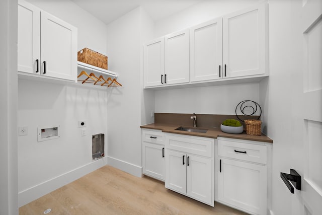 laundry room with sink, cabinets, light wood-type flooring, hookup for a washing machine, and electric dryer hookup