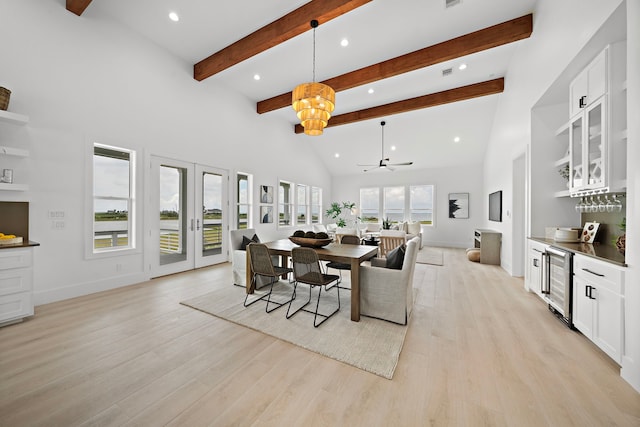 dining area featuring french doors, wine cooler, light hardwood / wood-style flooring, beamed ceiling, and a high ceiling