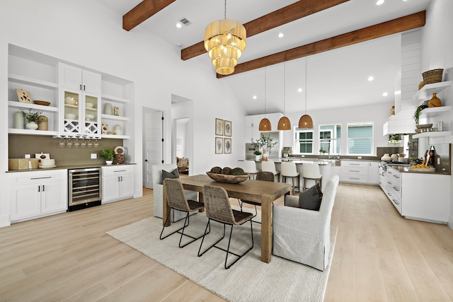 dining space featuring bar, beam ceiling, high vaulted ceiling, beverage cooler, and light hardwood / wood-style floors