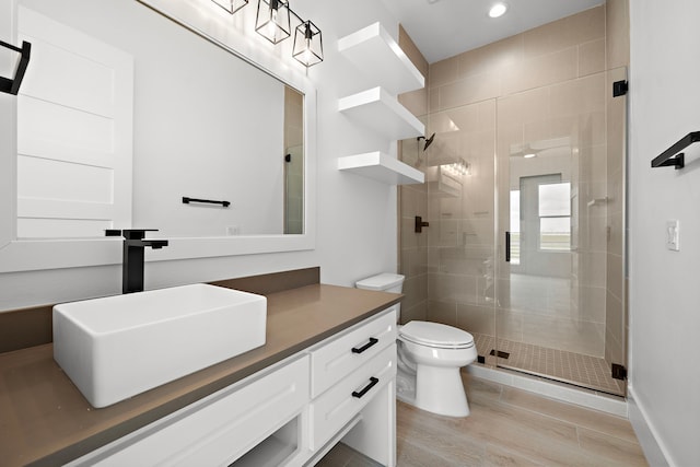 bathroom with hardwood / wood-style flooring, vanity, an enclosed shower, and toilet