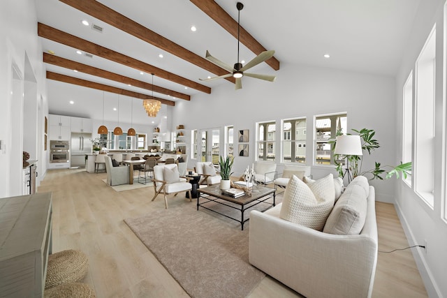 living room with a healthy amount of sunlight, ceiling fan with notable chandelier, beam ceiling, and light hardwood / wood-style flooring