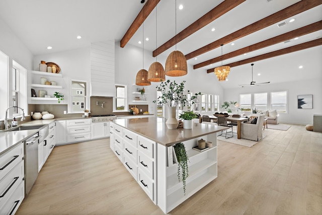 kitchen featuring sink, decorative light fixtures, dishwasher, beam ceiling, and white cabinets