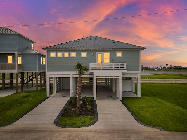 coastal home featuring a carport, a garage, a yard, and a balcony